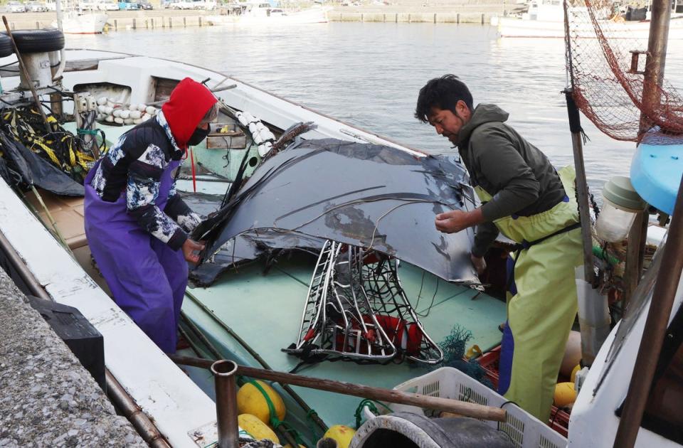 Fishermen participating in a searching operation unload recovered parts believed to be pieces of wreckage from the fuselage of a U.S. Air Force CV-22 ‘Osprey’ transport aircraft are from their boat at a port on Yakushima Island, Kagoshima Prefecture, Japan, 30 November 2023 (EPA)