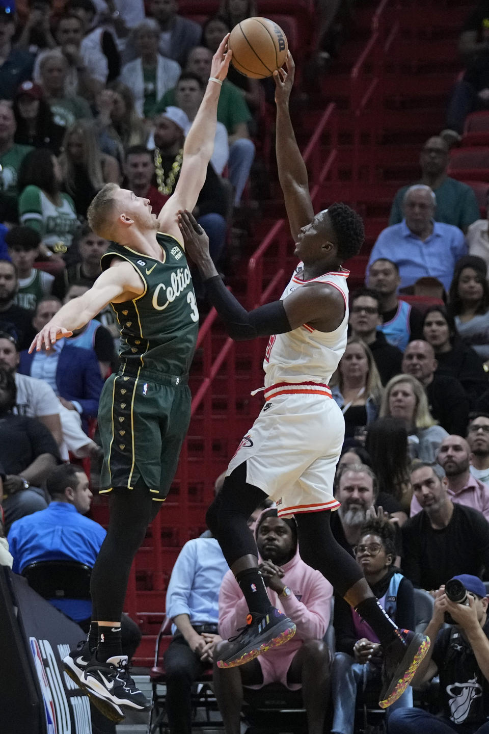 Boston Celtics forward Sam Hauser (30) rejects a shot from Miami Heat guard Victor Oladipo (4) during the first half of an NBA basketball game, Tuesday, Jan. 24, 2023, in Miami. (AP Photo/Wilfredo Lee)