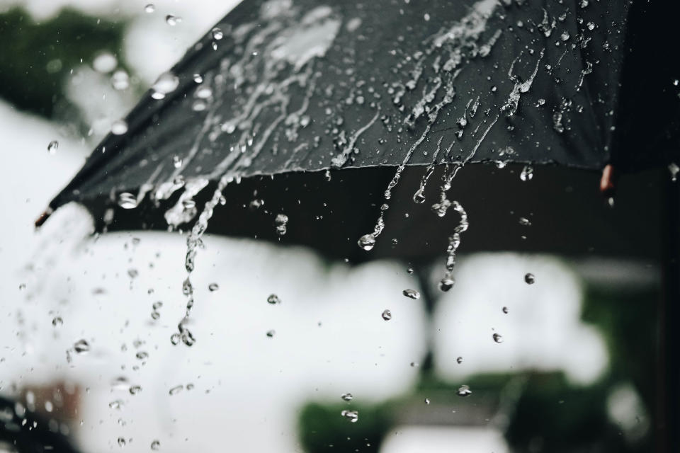 Schlechtes Wetter: Dicke Regentropfen fallen auf einen schwarzen Regenschirm