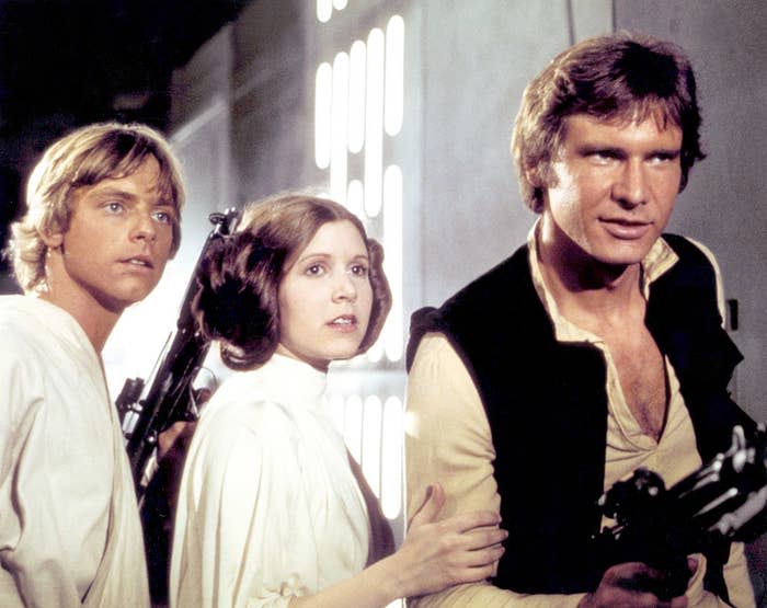 Luke Skywalker, Princess Leia, and Han Solo stand side-by-side in a scene from "Star Wars"