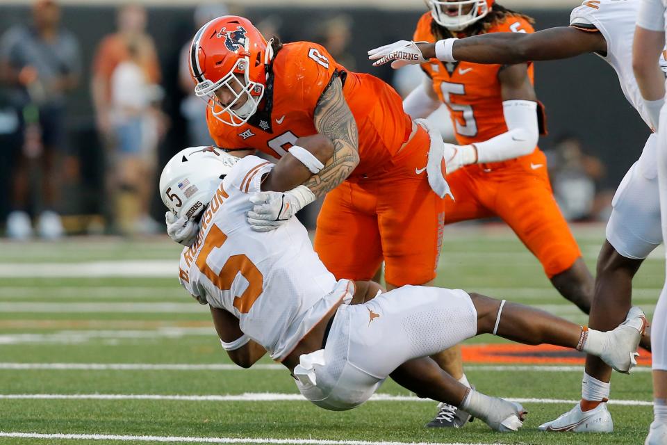 Oklahoma State Cowboys linebacker Mason Cobb (0) brings down <a class="link " href="https://sports.yahoo.com/ncaaw/teams/texas/" data-i13n="sec:content-canvas;subsec:anchor_text;elm:context_link" data-ylk="slk:Texas Longhorns;sec:content-canvas;subsec:anchor_text;elm:context_link;itc:0">Texas Longhorns</a> running back <a class="link " href="https://sports.yahoo.com/nfl/players/40055" data-i13n="sec:content-canvas;subsec:anchor_text;elm:context_link" data-ylk="slk:Bijan Robinson;sec:content-canvas;subsec:anchor_text;elm:context_link;itc:0">Bijan Robinson</a> (5) during a college football game between the Oklahoma State Cowboys (OSU) and the University of Texas Longhorns at Boone Pickens Stadium in Stillwater, Okla., Saturday, Oct. 22, 2022. Oklahoma State won 41-34.