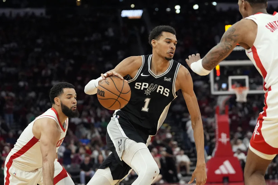 San Antonio Spurs' Victor Wembanyama (1) drives to the basket as Houston Rockets' Fred VanVleet, left, and Jabari Smith Jr. defend during the second half of an NBA basketball game Tuesday, March 5, 2024, in Houston. The Rockets won 114-101. (AP Photo/David J. Phillip)