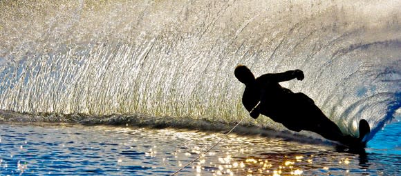 Dark silhouette of a waterskiing man taking a sharp turn.