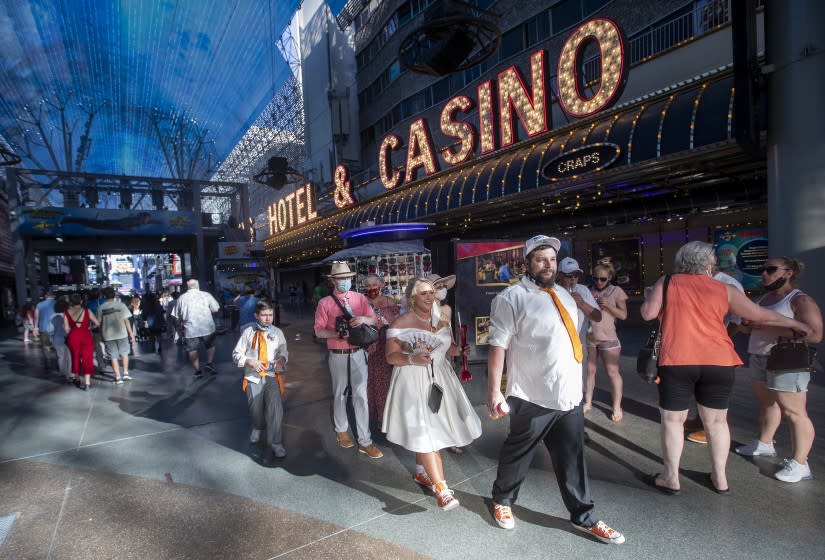 LAS VEGAS, CA - MAY 04, 2021: Newlyweds Kiley and Ryan Smith, from the State of Washington, walk with other tourists, while enjoying their wedding day along Freemont St. in downtown Las Vegas. The number of visitors to Las Vegas has been climbing consistently for months. (Mel Melcon / Los Angeles Times)