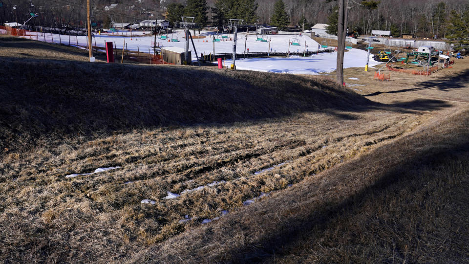 Afternoon sun casts shadows across the grassy half pipe in the snowboarding park at the Ski Bradford ski area, Tuesday, Feb. 14, 2023, in Bradford, Mass. For much of the Eastern United States, the winter of 2023 has been a bust. Snow totals are far below average from Boston to Philadelphia in 2023 and warmer temperatures have often resulted in more spring-like days than blizzard-like conditions. (AP Photo/Charles Krupa)