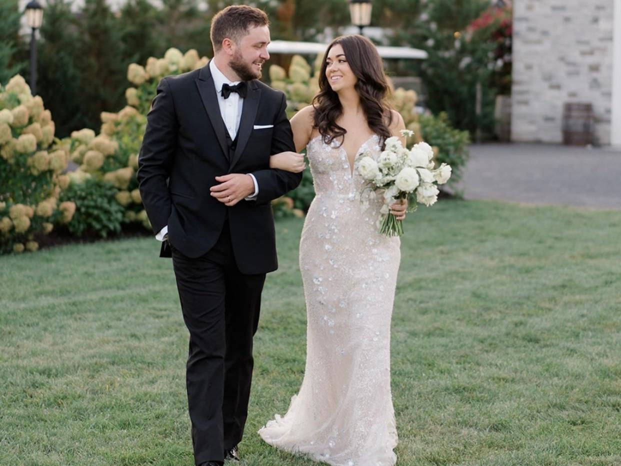 A bride and groom walk together arm in arm.