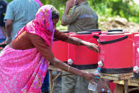 MUMBAI, MAHARASHTRA, INDIA - 2020/05/13: A woman fills her water bottle as they wait to board vehicles during the lockdown. Due to lockdown situation, most migrants are stuck in Mumbai, some walk and others arrange their own trucks and buses to their home towns, while the police say that the buses are available by the government. (Photo by Ratika More/SOPA Images/LightRocket via Getty Images)