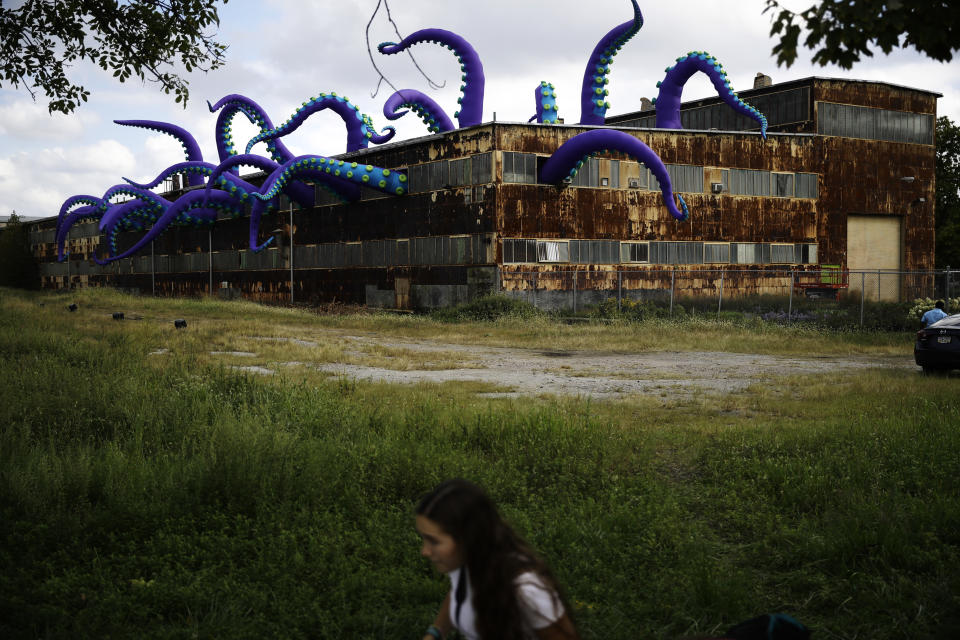 An inflatable sculpture entitled "Sea Monsters HERE" extends from a rusting warehouse called Building 61 at the Navy Yard in Philadelphia, Tuesday, Oct. 9, 2018. The installation was created by UK-based artists Filthy Luker and Pedro Estrellas. The former military base is free and open to the public. (AP Photo/Matt Rourke)