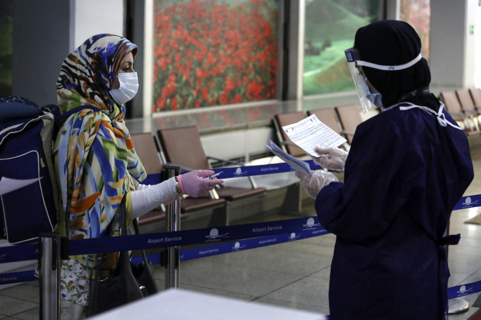 A health worker, right, checks the health declaration form of a passenger on an Emirates plane upon arrival at terminal of Tehran's Imam Khomeini airport, Iran, Friday, July 17, 2020. The first Emirates flight arrived in Iran after nearly 5 months of suspension of the most airliners flights to the country due to the coronavirus outbreak, as Iranian officials at the airport say they are doing everything possible to ensure passengers are not infected, and isolate those with symptoms. (AP Photo/Vahid Salemi)