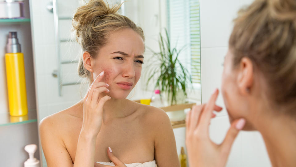 Woman looking at her skin in the mirror