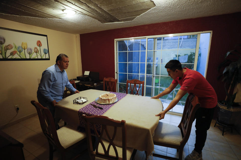 Alejandro Canejo Lopez, left, and his son Daniel, 16, move the dining room table so they can add an extra table to increase distancing between guests, as they prepare to celebrate the 15th birthday of Ximena Canejo Hernandez along with a small group of close relatives, in Tlalnepantla, just outside Mexico City, Monday, July 13, 2020. Ximena's family, wanting to give her a traditional Quinceanera, had booked a church and event hall for July 18 long before the coronavirus pandemic hit, but the celebration has now been postponed until late November.(AP Photo/Rebecca Blackwell)