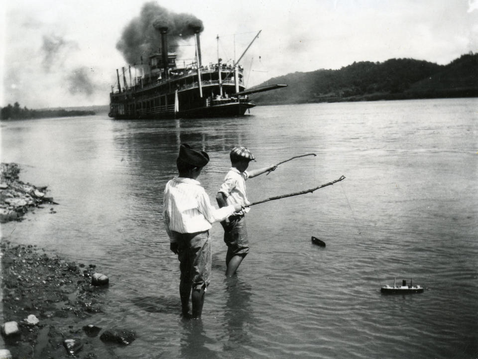 Children playing with toy boats on the river's edge as a steamboat passes in Rising Sun, Indiana, 1919. (Photo by Felix Koch/Cincinnati Museum Center/Getty Images)