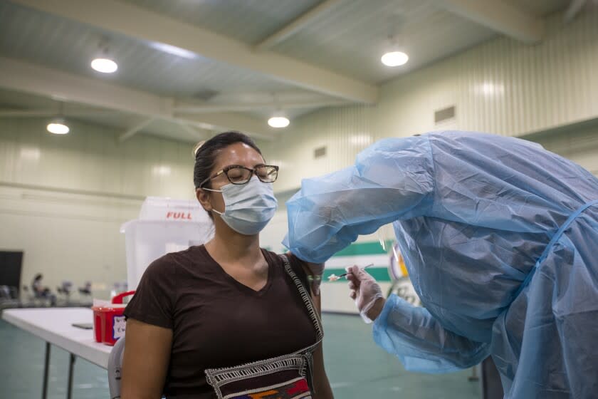 Eagle Rock, CA - August 30: A nurse gives a Pfizer-BioNTech vaccine shot to Roxanne Juarez, special education assistant at Fletcher Drive Elementary, at Eagle Rock High School, as Los Angeles County Board of Supervisors Chair Hilda Solis, Interim Superintendent Megan K. Reilly, School Board members Kelly Gonez and Jackie Goldberg and special guests visit Los Angeles Unified School-based mobile vaccination clinics at Eagle Rock High School on Monday, Aug. 30, 2021 in Eagle Rock, CA. All employees in the Los Angeles Unified School District must be vaccinated against COVID-19 by Oct. 15, an order that puts it at the forefront of school systems across the country that are mandating strict coronavirus safety measures for employees and students. (Allen J. Schaben / Los Angeles Times)