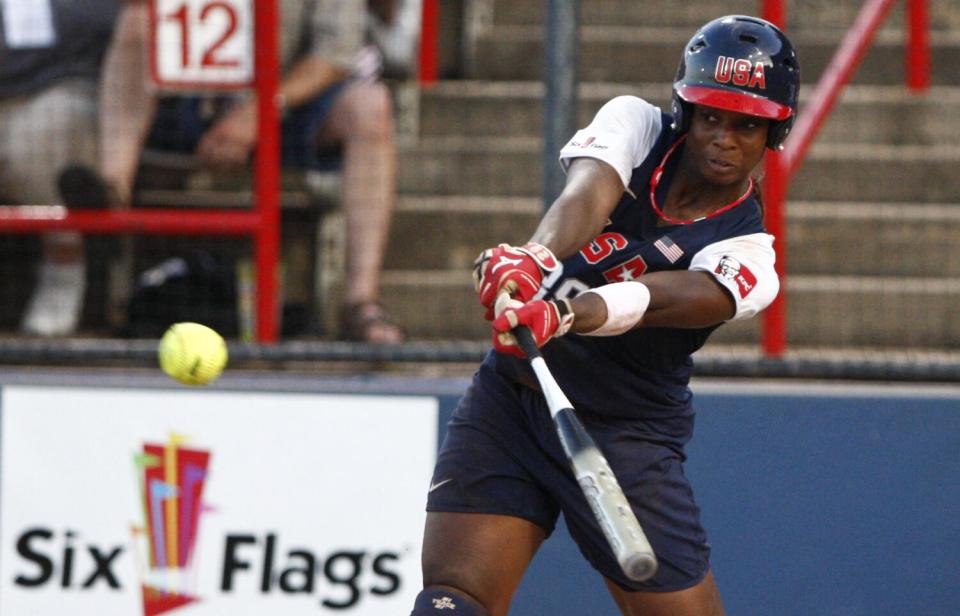 A woman in a softball uniform bats in a game