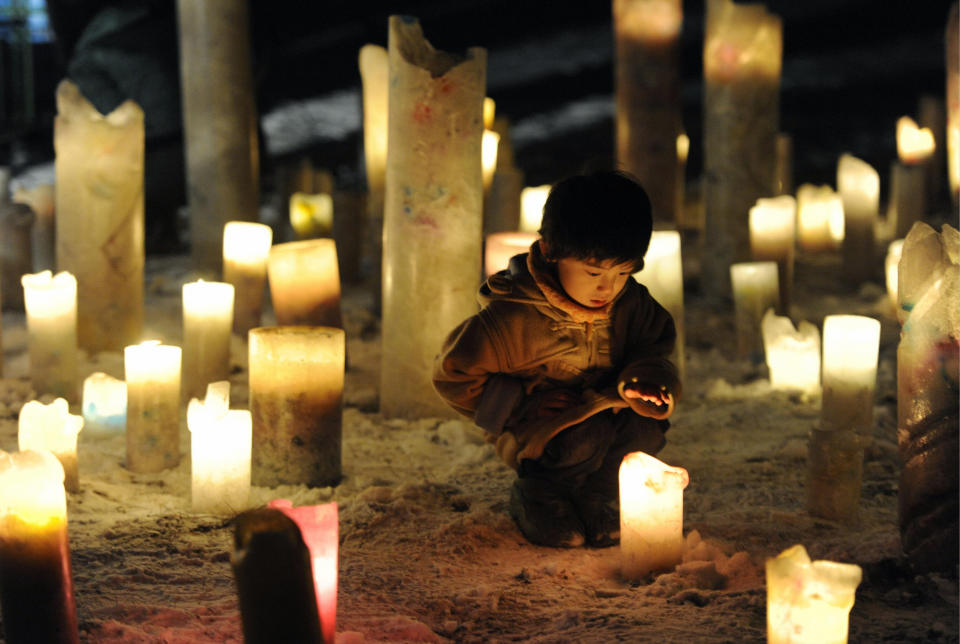 一位兒童在前幾年3月11日的重建祈禱活動中，看著燭火，圖片來源：日本共同社／REUTERS。