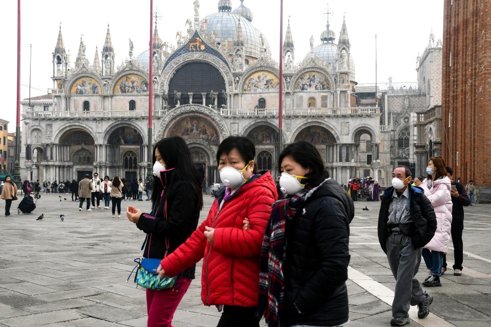 Tourists wearing protective facemasks visit the Piazza San Marco, in Venice, on February 24, 2020 during the usual period of the Carnival festivities which the last two days have been cancelled due to an outbreak of the COVID-19 the novel coronavirus, in northern Italy. - Italy reported on February 24, 2020 its fourth death from the new coronavirus, an 84-year old man in the northern Lombardy region, as the number of people contracting the virus continued to mount. (Photo by ANDREA PATTARO / AFP) (Photo by ANDREA PATTARO/AFP via Getty Images)