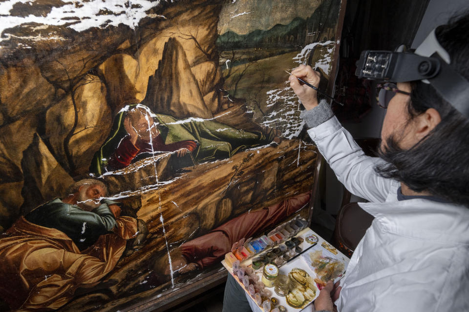 La restauradora Valentina Piovan trabaja en la pintura de Vittore Carpaccio "La agonía en el jardín" de 1502 en la Escuela Dálmata en Venecia, en el norte de Italia el 7 de diciembre de 2022. Una exposición de las pinturas de Carpaccio llegará a Venecia en marzo tras su paso por la Galería Nacional de Washington donde se presentará hasta el 12 de febrero de 2023. (Foto AP/Domenico Stinellis)