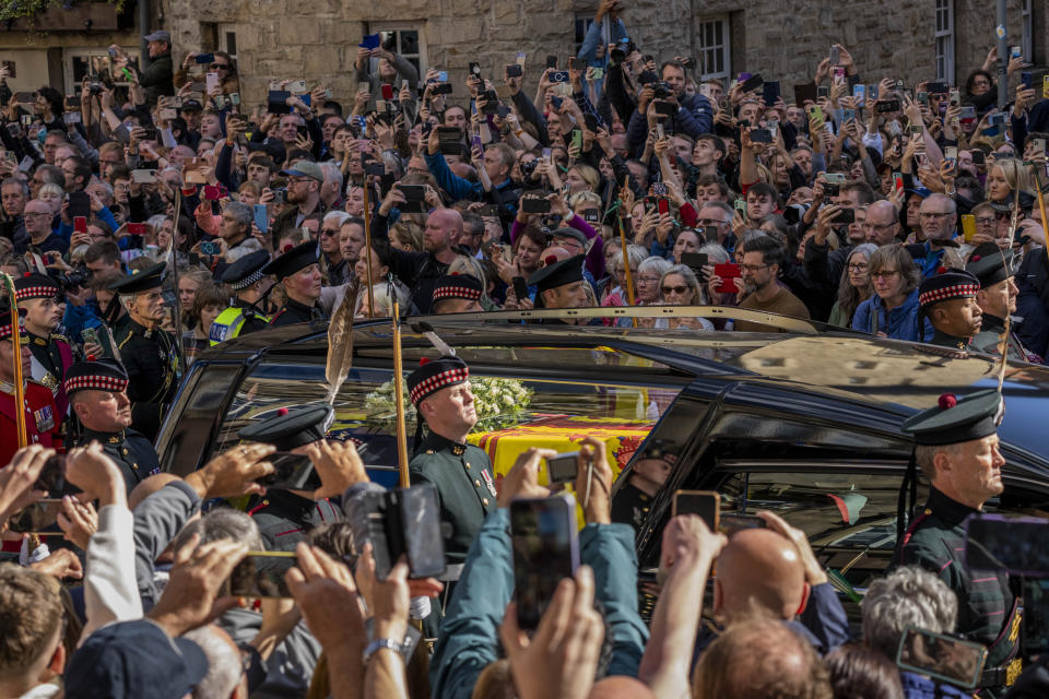 People attend the procession of Queen Elizabeth II's coffin, from the Palace of Holyroodhouse to St Giles Cathedral, on the Royal Mile in Edinburgh, Scotland, Monday Sept. 12, 2022. Britain's longest-reigning monarch who was a rock of stability across much of a turbulent century, died Thursday Sept. 8, 2022, after 70 years on the throne. She was 96. (AP Photo/Bernat Armangue)