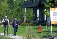 Police investigators walk past a condo building in Longueil