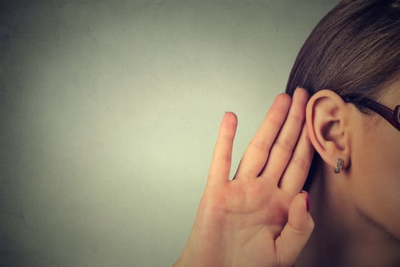 Woman listening with hand to ear