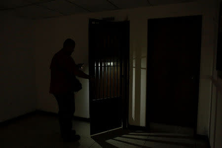 A worker uses light from a phone while he opens a door at the Padre Justo hospital, during a blackout in Rubio, Venezuela March 14, 2018. Picture taken March 14, 2018. REUTERS/Carlos Eduardo Ramirez