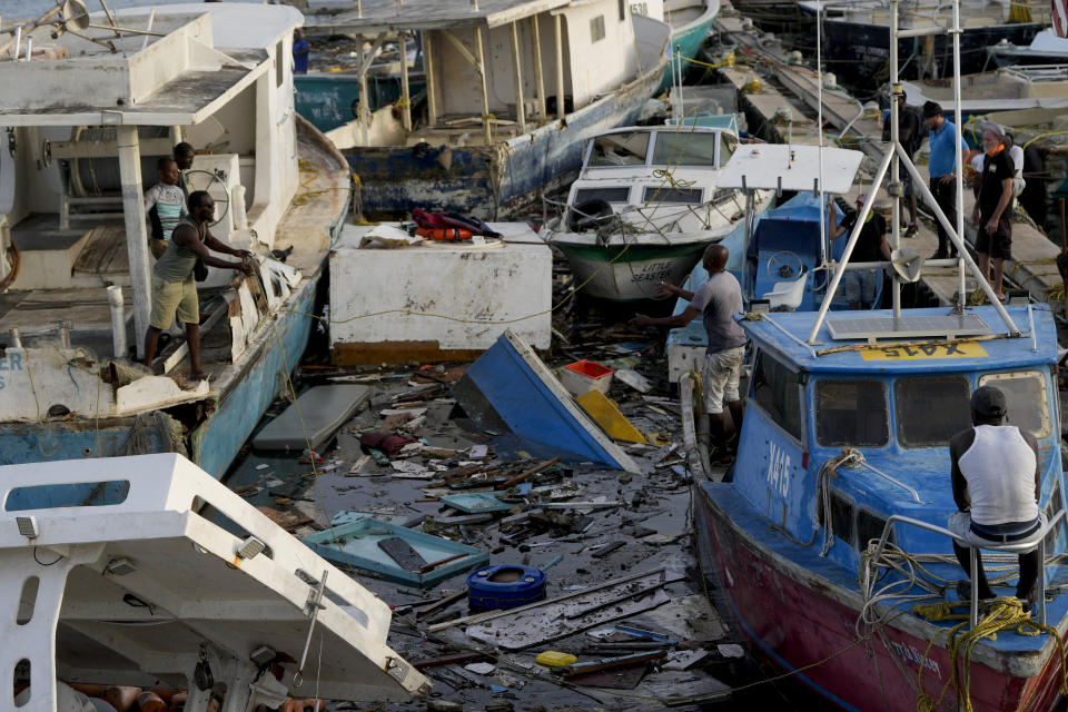 A fisherman throws a rope across boats damaged by Hurricane Beryl at Bridgetown Fisheries, Barbados, Tuesday, July 2, 2024. (AP Photo/Ricardo Mazalan)