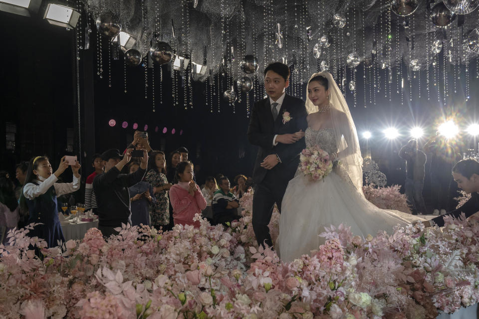 Bride Chen Yaxuan and groom Dou Di walk down the stage during an unmasked wedding banquet in Beijing on Saturday, Dec. 12, 2020. Lovebirds in China are embracing a sense of normalcy as the COVID pandemic appears to be under control in the country where it was first detected. (AP Photo/Ng Han Guan)
