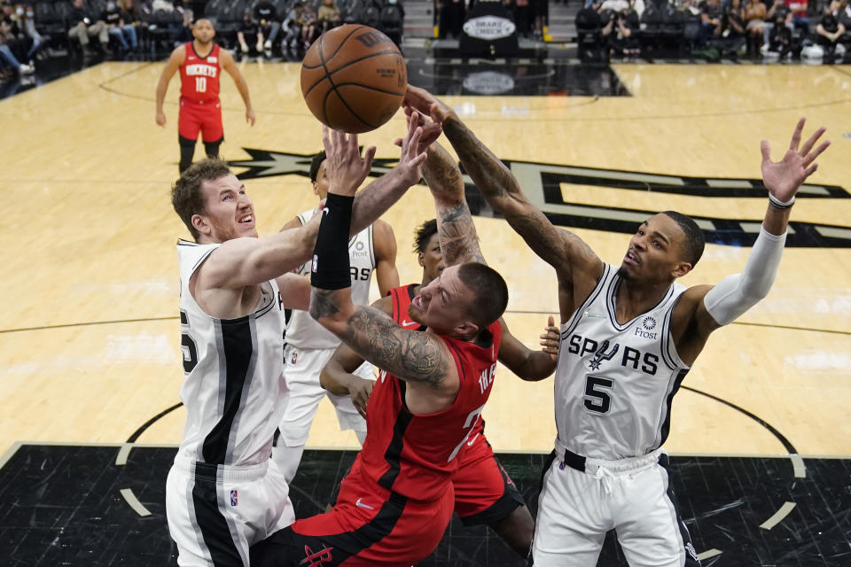 Houston Rockets center Daniel Theis, center, is blocked as he drives to the basket against San Antonio Spurs center Jakob Poeltl, left, and guard Dejounte Murray (5) during the first half of an NBA basketball game, Wednesday, Jan. 12, 2022, in San Antonio. (AP Photo/Eric Gay)