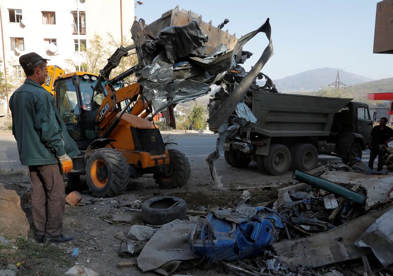 Workers remove debris near a residential building, which was damaged during the military conflict over the breakaway region of Nagorno-Karabakh, in Stepanakert