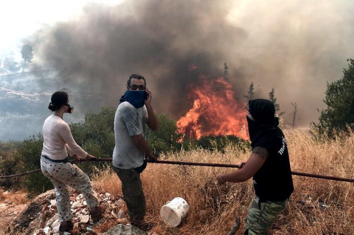 People stand in front of a fire in Athens on July 17, 2015. Greece appealed for EU help to battle wildfires raging on the outskirts of Athens and in the southern Peloponnese region that forced the evacuation of several villages (AFP Photo/Aris Messinis)