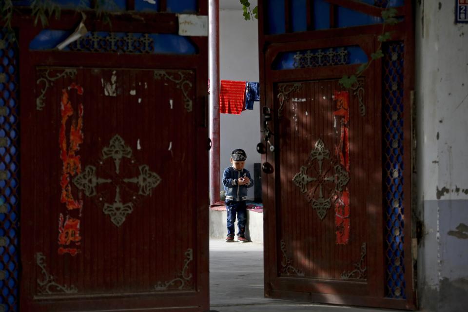 FILE - In this Sept. 20, 2018, file photo, an Uighur child plays alone in the courtyard of a home at the Unity New Village in Hotan, in western China's Xinjiang region. The prominent British human rights lawyer Geoffrey Nice is convening an independent tribunal in London with public hearings in 2021, to look into the Chinese government's alleged rights abuses against the Uighur Muslim minority in the far western province of Xinjiang.(AP Photo/Andy Wong, FILE)