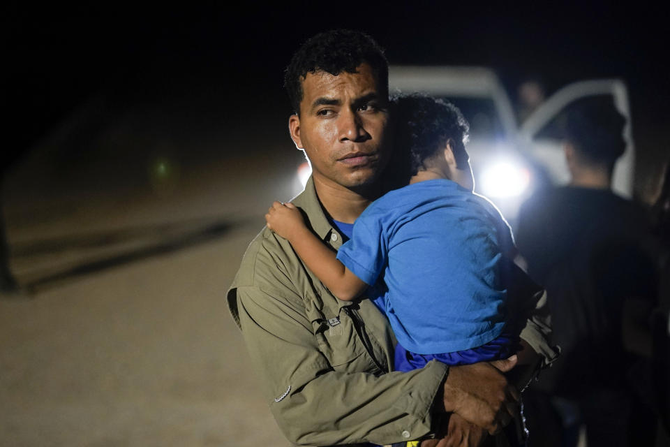 FILE - A migrant from Peru holds his son as he waits to be processed by U.S. Border Patrol agents near the end of a border wall near Yuma, Arizona, Aug. 23, 202. (AP Photo/Gregory Bull, File)