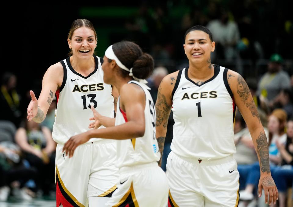 Las Vegas Aces forward Cayla George (13) celebrates a 105-64 win over the Storm with teammates Sydney Colson (51) and Kierstan Bell (1) after a WNBA game Saturday, May 20, 2023, in Seattle.