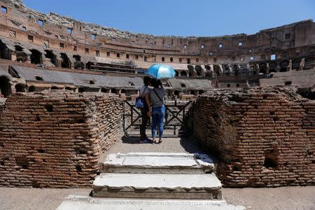 Tourists use an umbrella to protect themselves from the sun as they visit the Colosseum in Rome, Italy, July 1, 2016. REUTERS/Alessandro Bianchi