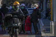 Motorists pass by an elderly woman with her groceries in Beijing, Thursday, Dec. 1, 2022. A campaign to vaccinate the elderly has sparked hopes China might roll back severe anti-virus controls that prompted protesters to demand President Xi Jinping resign, but the country faces daunting hurdles and up to a year of hard work before "zero COVID" can end. (AP Photo/Andy Wong)