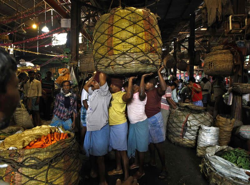 Workers carry a packed basket of vegetables at a wholesale vegetable market in Kolkata February 27, 2015. REUTERS/Rupak De Chowdhuri