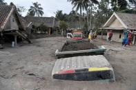 Trucks covered by volcanic ash which is spewed out of Mount Semeru are see in Sumber Wuluh Village