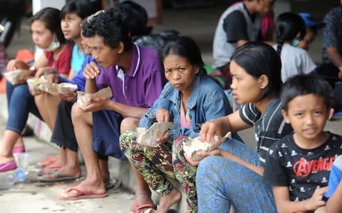 Villagers eat at an evacuation centre in Karangasem on the Indonesian resort island of Bali  - Credit: SONNY TUMBELAKA/AFP/Getty Images