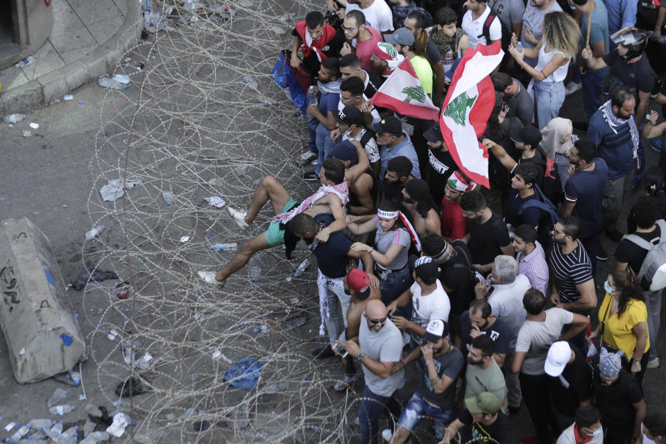 Anti-government protesters try to remove a barbed-wire barrier to advance towards the government buildings during a protest in Beirut, Lebanon, Saturday, Oct. 19, 2019. The blaze of protests was unleashed a day earlier when the government announced a slate of new proposed taxes, including a $6 monthly fee for using Whatsapp voice calls. The measures set a spark to long-smoldering anger against top leaders from the president and prime minister to the numerous factional figures many blame for decades of corruption and mismanagement. (AP Photo/Hassan Ammar)