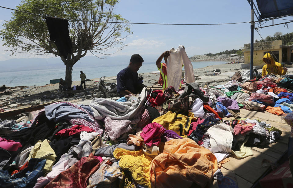 Evacuees check used clothes outside tents after their homes were destroyed by the massive earthquake and tsunami in Loly, Central Sulawesi, Indonesia Friday, Oct. 5, 2018. French rescuers say they've been unable to find the possible sign of life they detected a day earlier under the rubble of a hotel that collapsed in the earthquake a week ago on Indonesia's Sulawesi island. (AP Photo/Tatan Syuflana)