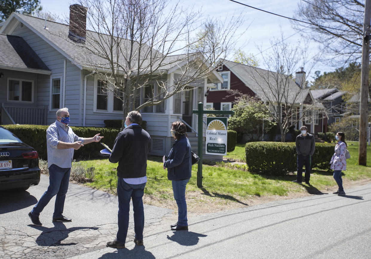 Rick Nazarro of Colonial Manor Realty talks with a pair of interested buyers in the driveway as a couple waits to enter a property he is trying to sell during an open house in Revere, MA.  (Credit: Blake Nissen for The Boston Globe via Getty Images)