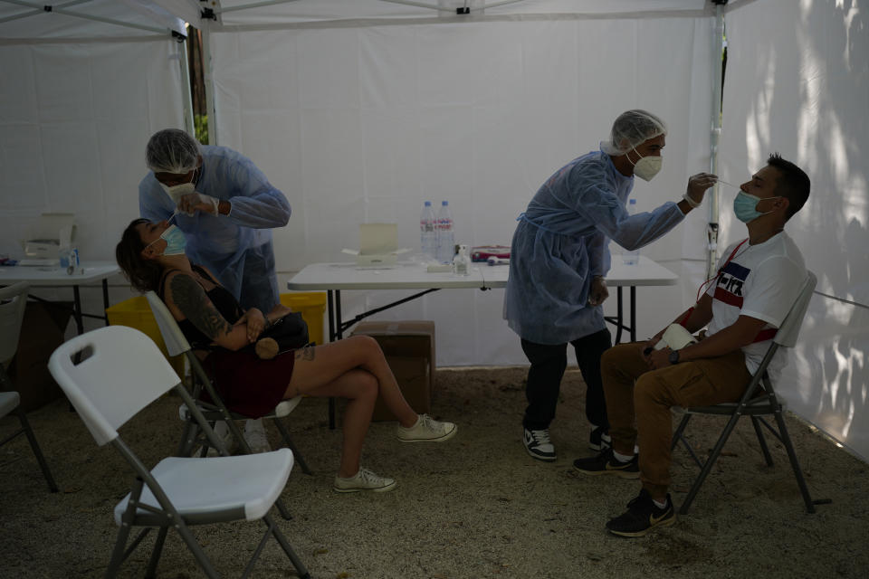 Visitors take a covid-19 test at the entrance of the Eiffel Tower in Paris, Wednesday, July 21, 2021. Visitors now need a special COVID pass to ride up the Eiffel Tower or visit French museums or movie theaters, the first step in a new campaign against what the government calls a "stratospheric" rise in delta variant infections. (AP Photo/Daniel Cole)