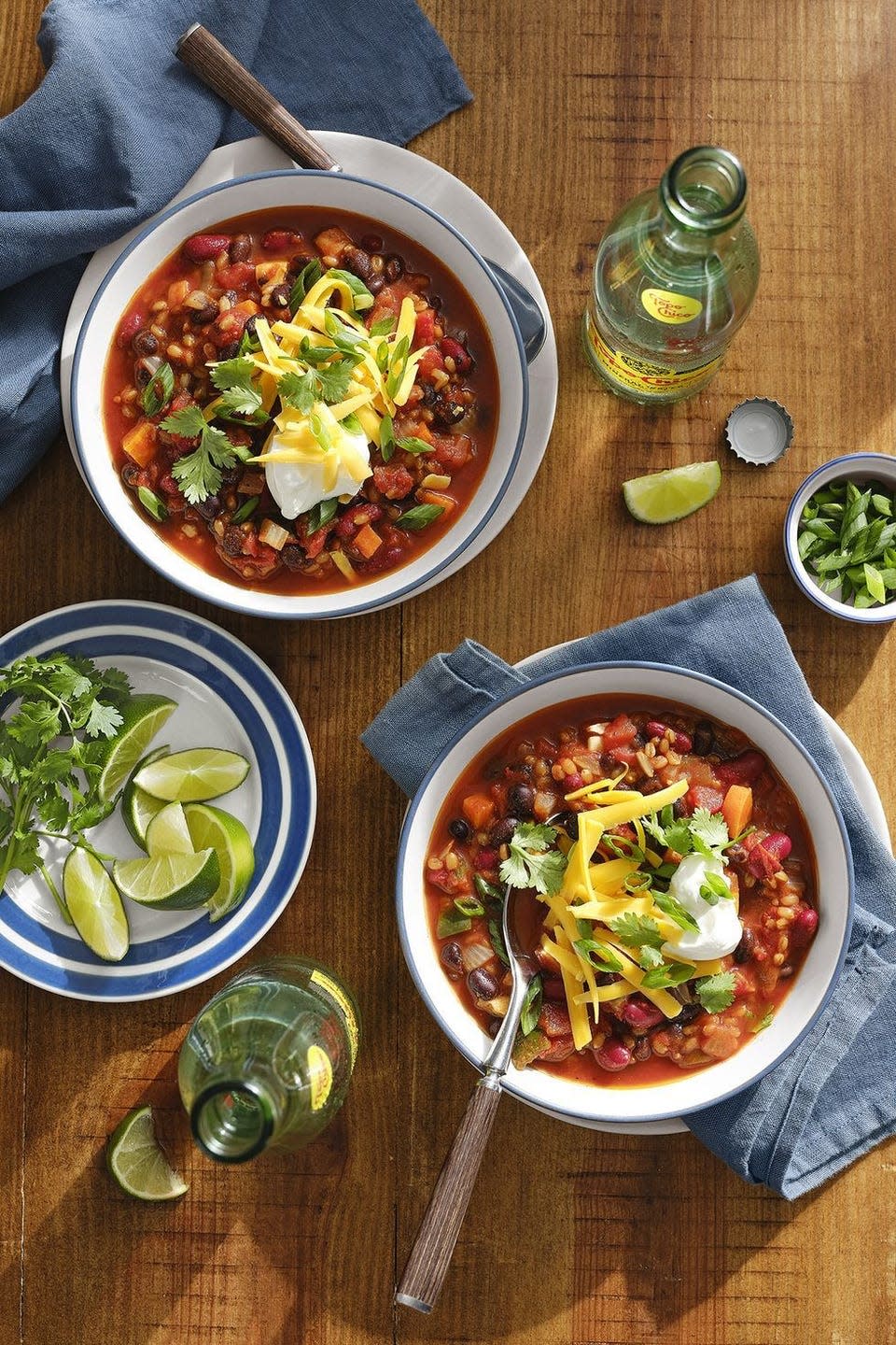 two bowls of vegetarian chili with sour cream and shredded cheese and cilantro no top