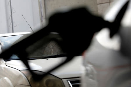 A woman is seen through a fuel nozzle as she waits in a queue at a gas station during the ongoing blackout in Caracas, Venezuela March 10, 2019. REUTERS/Carlos Jasso