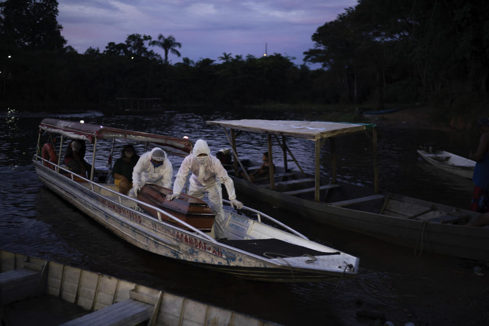 FILE - In this May 14, 2020 file photo, SOS Funeral workers transport by boat the coffin containing the body of a suspected COVID-19 victim that died in a river-side community near Manaus, Brazil. Navigating complex waterways to reach remote communities in Brazil’s Amazon is only the first challenge for health workers vaccinating Indigenous and riverine people against COVID-19. Upon arrival, they face something they never anticipated: people refusing to take the shot. (AP Photo/Felipe Dana, File)