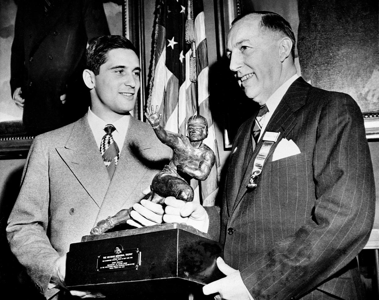 Johnny Lujack, left, field general of the 1947 Notre Dame football team, receives the Heisman Memorial Trophy at the Downtown Athletic Club in New York City on Dec. 10, 1947. Presenting the award is Wilbur Jurden, president of the Downtown A.C. (AP Photo/Jacob Harris)