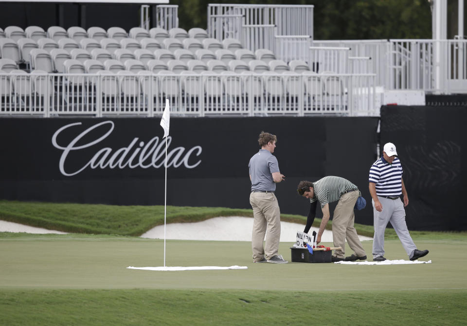 Course workers tend to the 18th hole of the newly redesigned Blue Monster, site of this week's Cadillac Championship golf tournament, Wednesday, March 5, 2014, in Doral, Fla. (AP Photo/Wilfredo Lee)