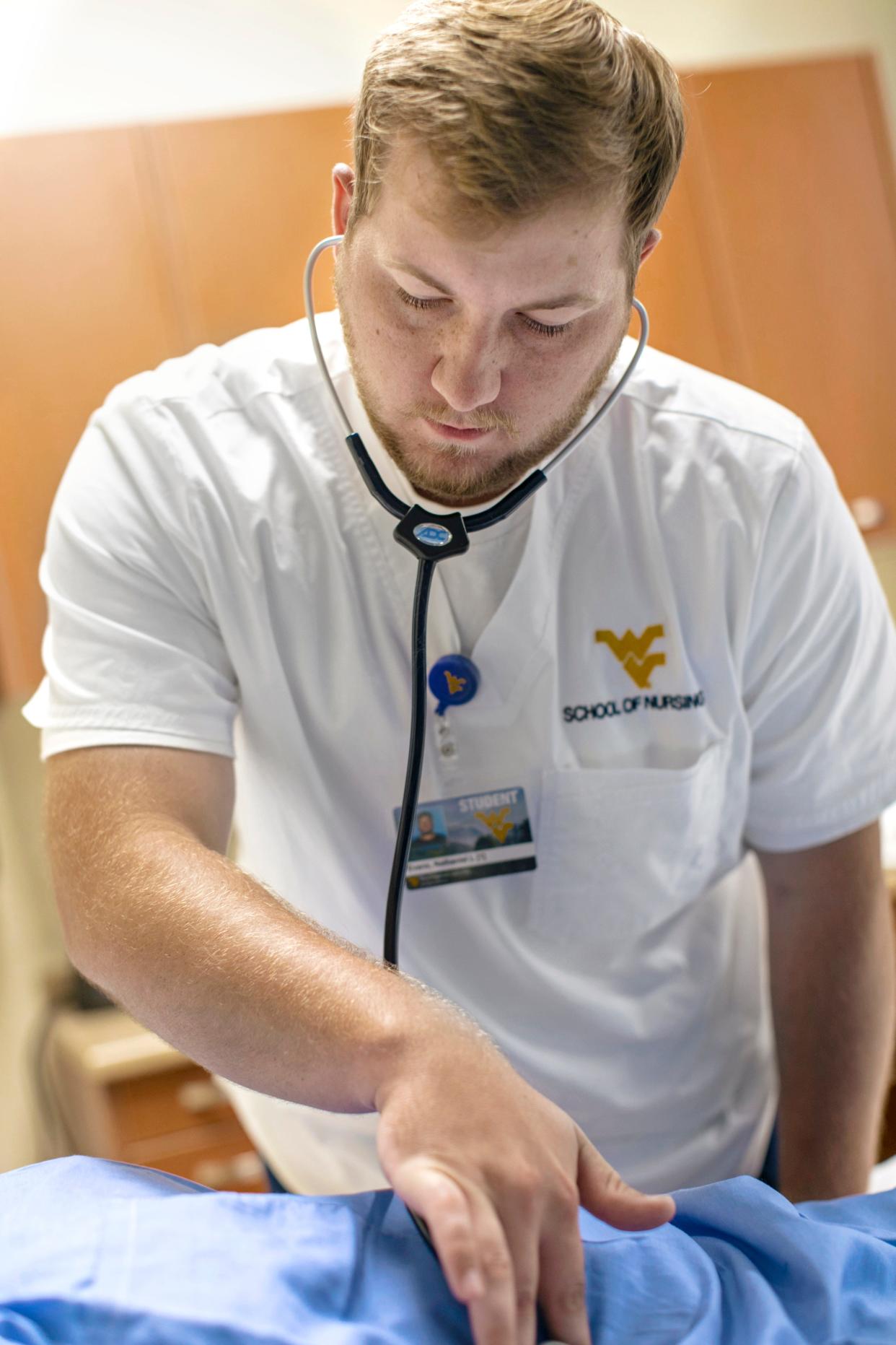 Recent graduate Nathaniel Evans from Mt. Storm attends to a patient while earning his BSN degree at the WVU School of Nursing Potomac State College. The BSN program is accepting applications for fall semester through March 15, 2022.