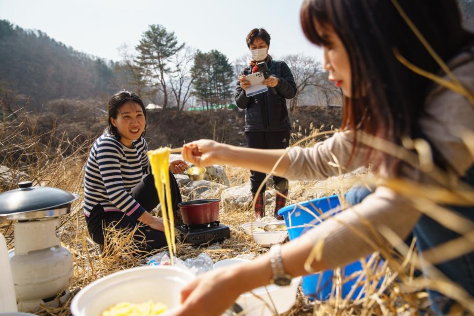 Two women make food outdoors