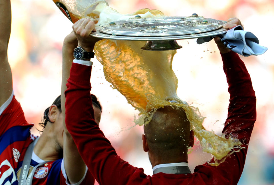 Munich's coach Pep Guardiola from Spain gets a beer shower by Belgian player Daniel van Buyten, left, as celebrates with the German championships trophy at the end of the German Bundesliga soccer match between FC Bayern Munich and VfB Stuttgart at Allianz Arena in Munich, Germany, Saturday May 10, 2014. (AP Photo/dpa,Andreas Gebert)